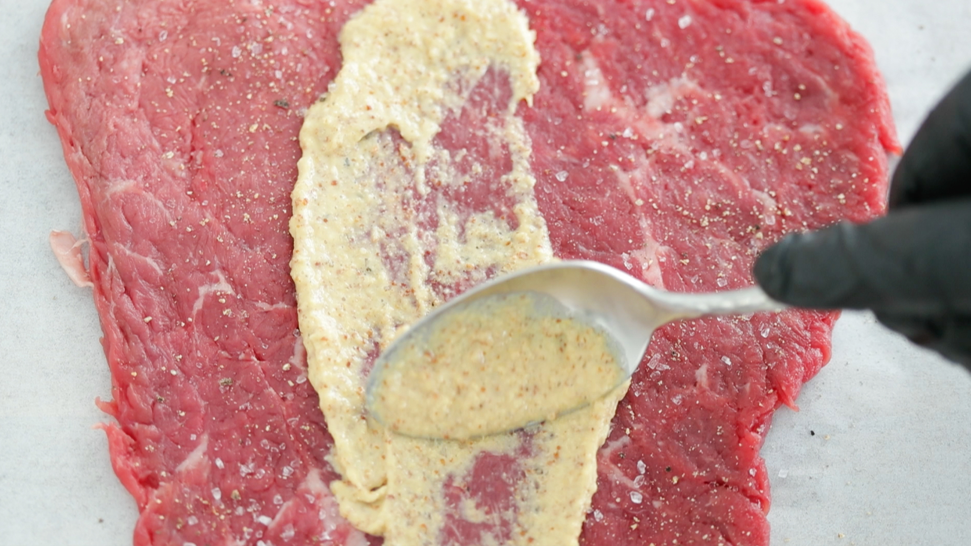 spreading mustard on steak
