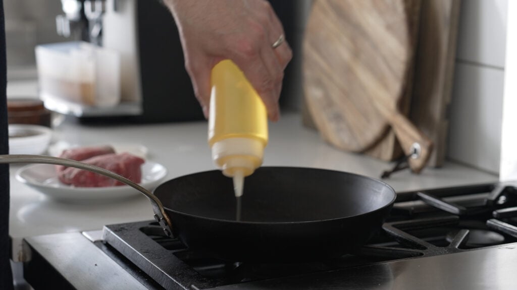 Adding oil to a cast iron pan on the stove