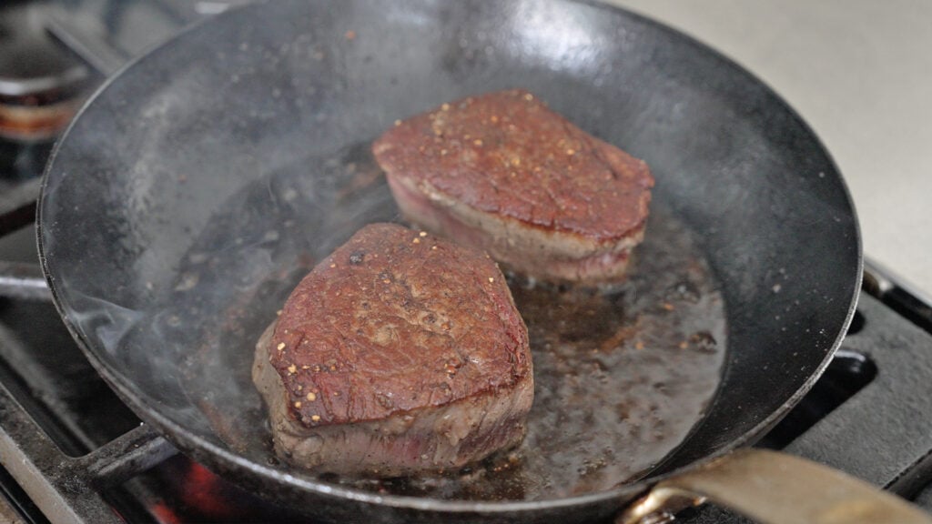 pieces of browned beef in a cast iron skillet