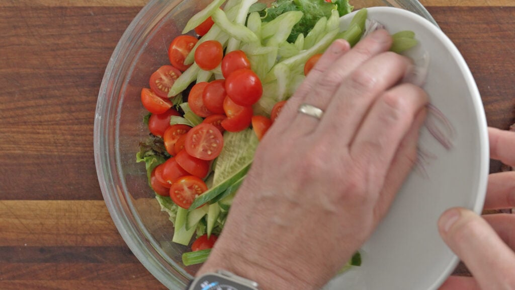 salad ingredients added to a bowl