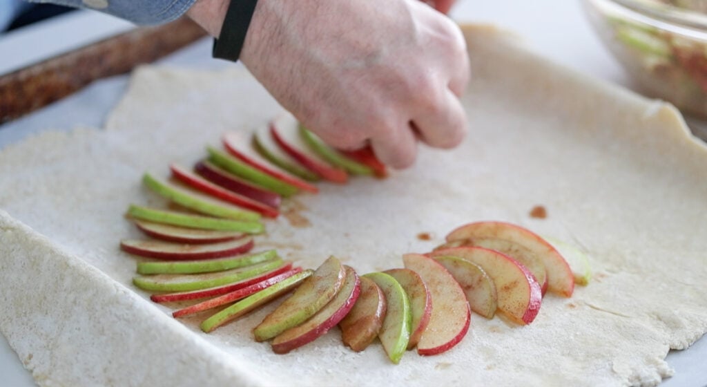 adding sliced apples to pie dough