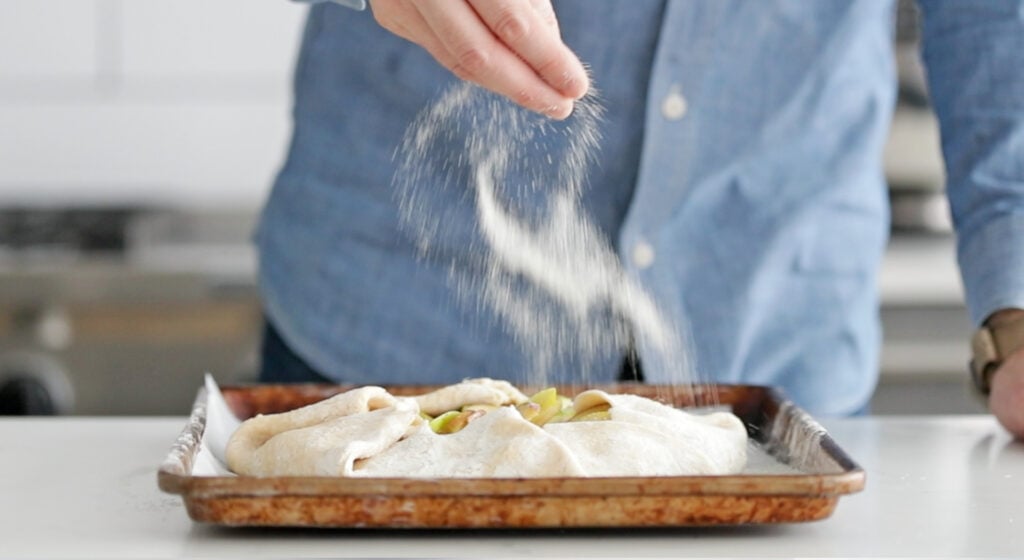 sprinkling sugar onto an apple galette