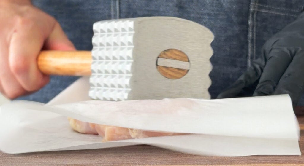 Pounding the chicken breasts between parchment