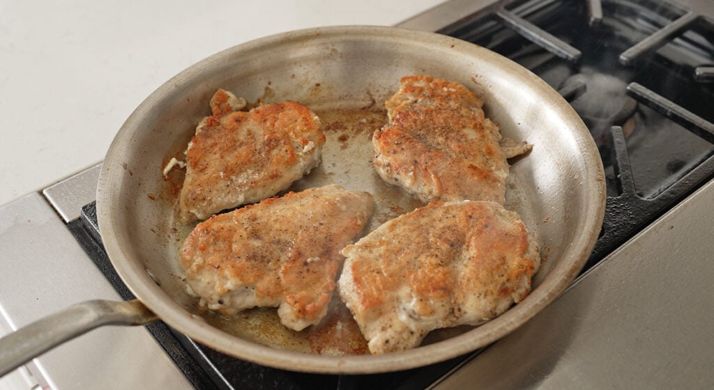 searing the chicken in a stainless stee pan