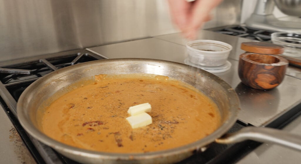 adding butter cubes to sauce mixture