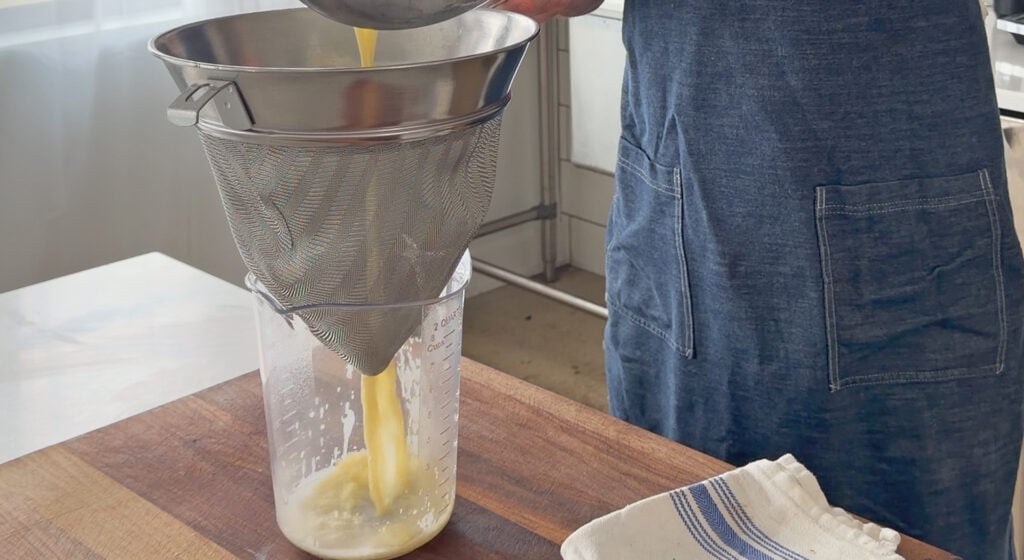 Straining the mixture through a fine-mesh strainer