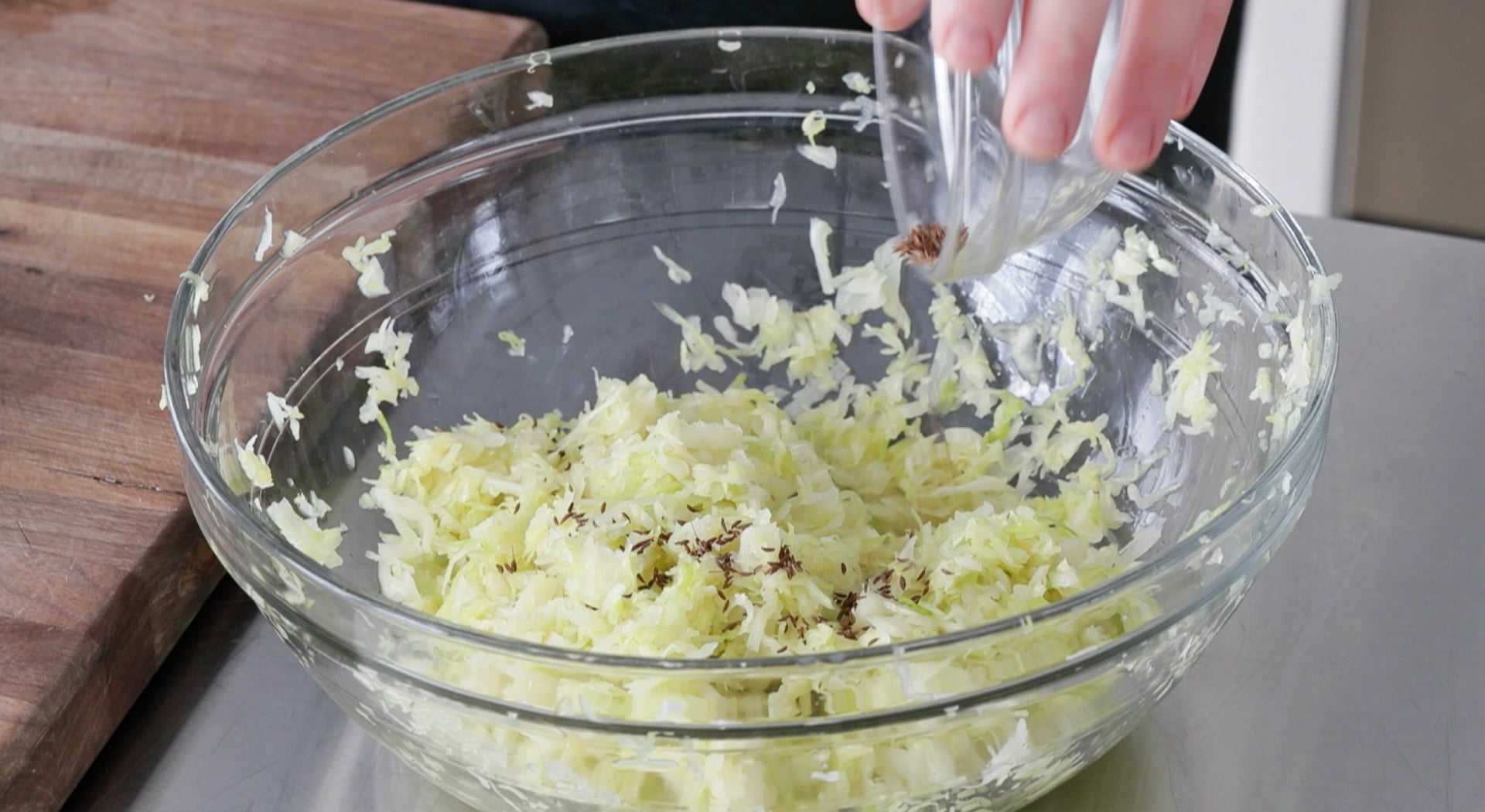 adding caraway seeds to salted cabbage