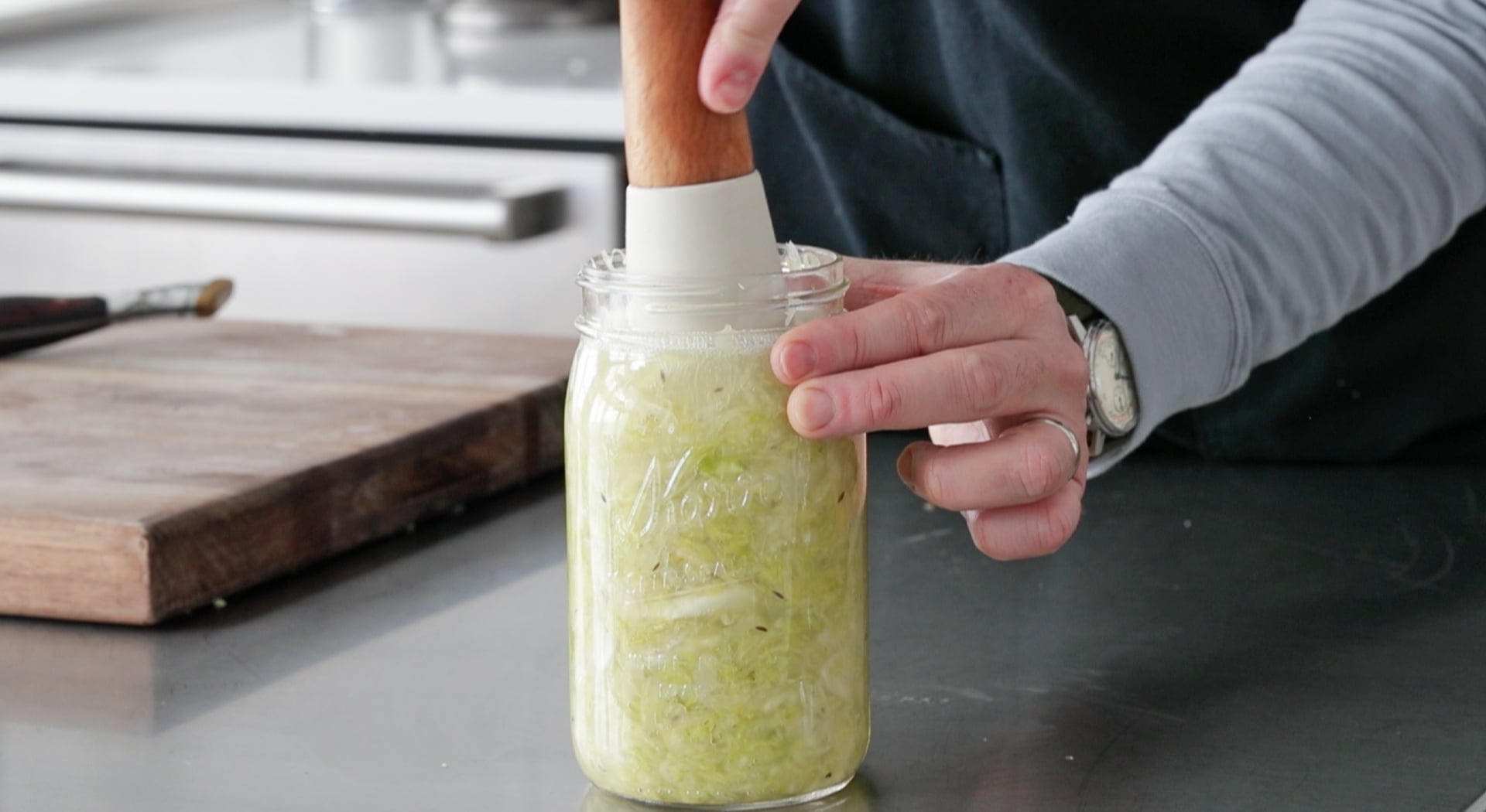 mashing down sauerkraut in a jar