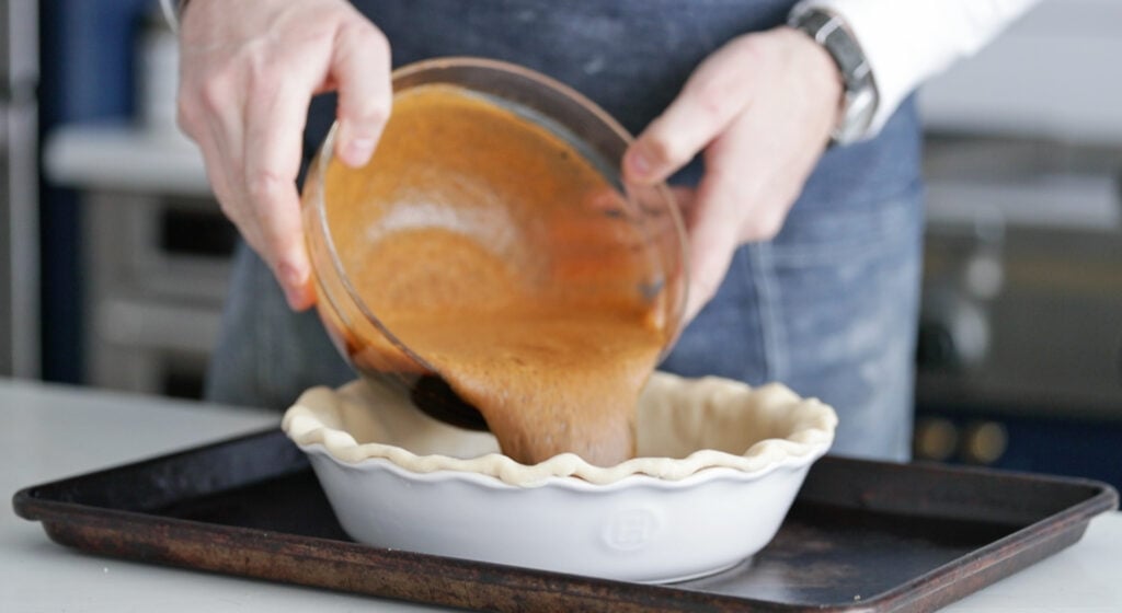 pouring a molasses filling into a pie crust