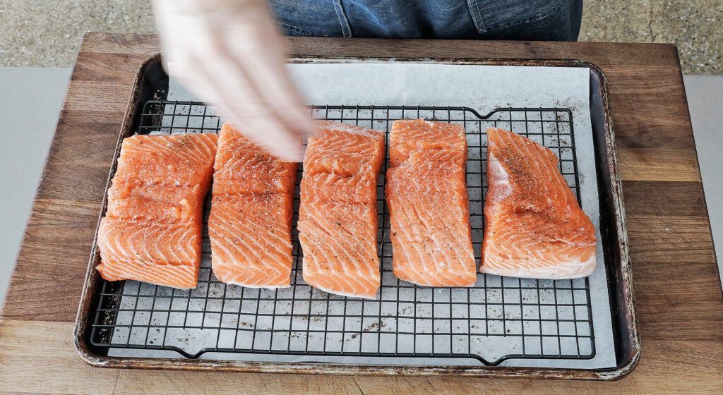 Skin-on salmon fillets seasoned with salt and pepper resting uncovered