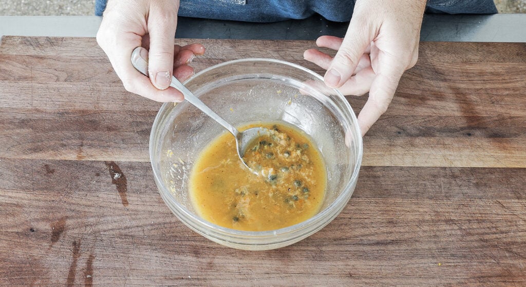 Melted butter, grated garlic, lemon and orange zest, Dijon, paprika, and capers whisked together in a bowl.