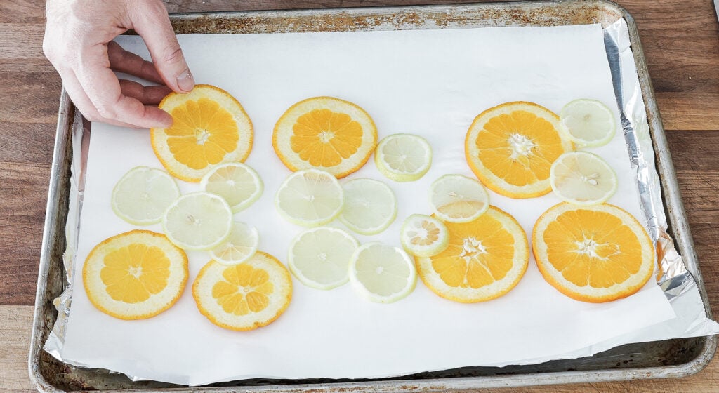 Lemon and orange slices arranged on parchment-lined foil sheet tray