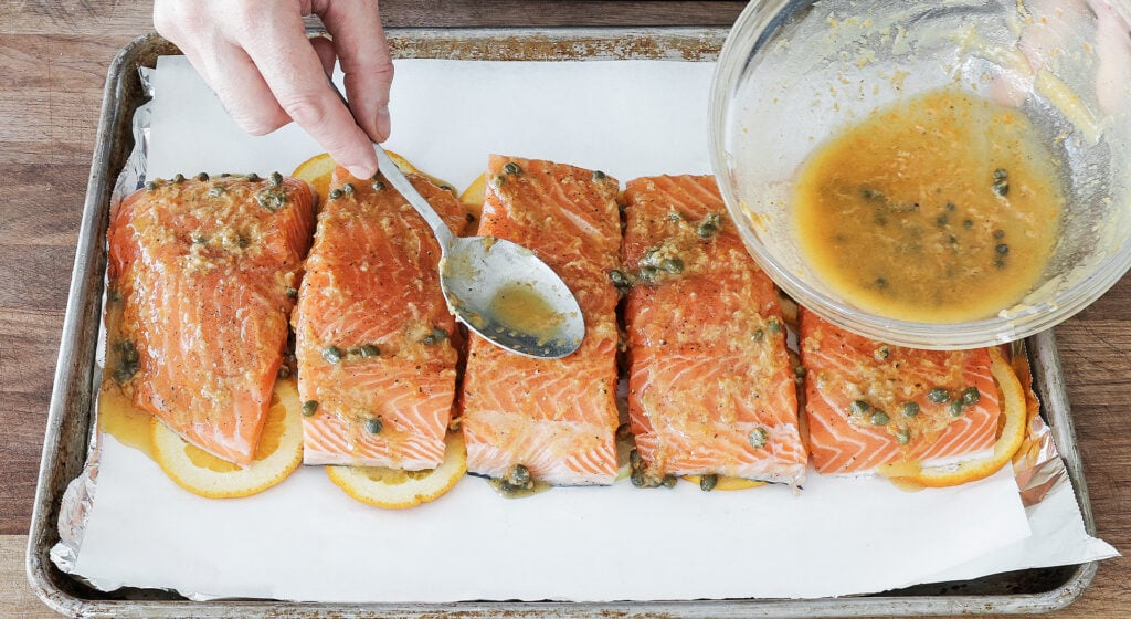 Salmon fillets set skin-side down on citrus slices and drizzled with garlic butter sauce