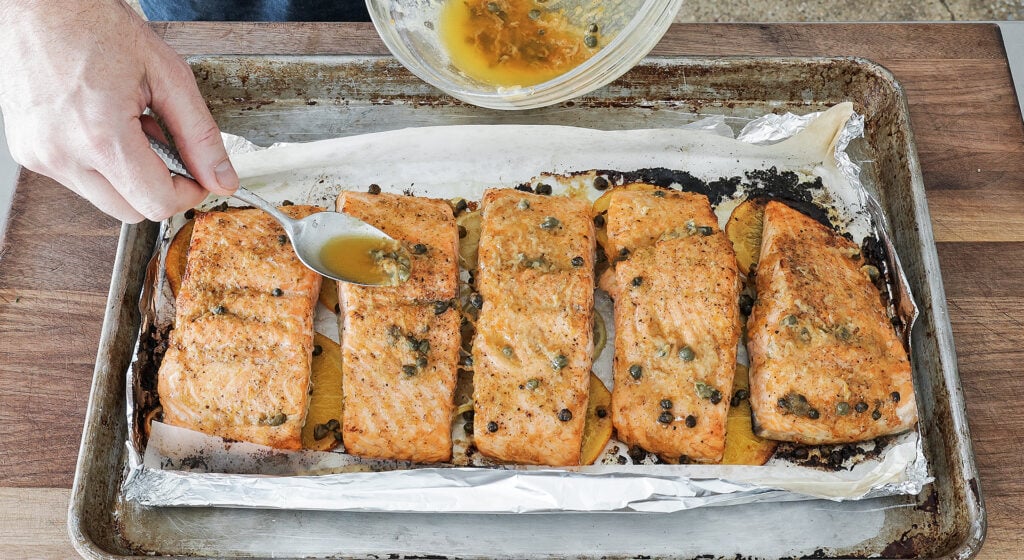 Baked salmon resting while the remaining garlic butter sauce is spooned over the top