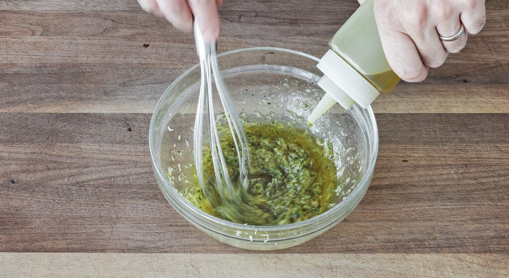 Grated garlic, lemon zest, thyme, rosemary, Dijon, and olive oil whisked into a loose herb marinade in a bowl