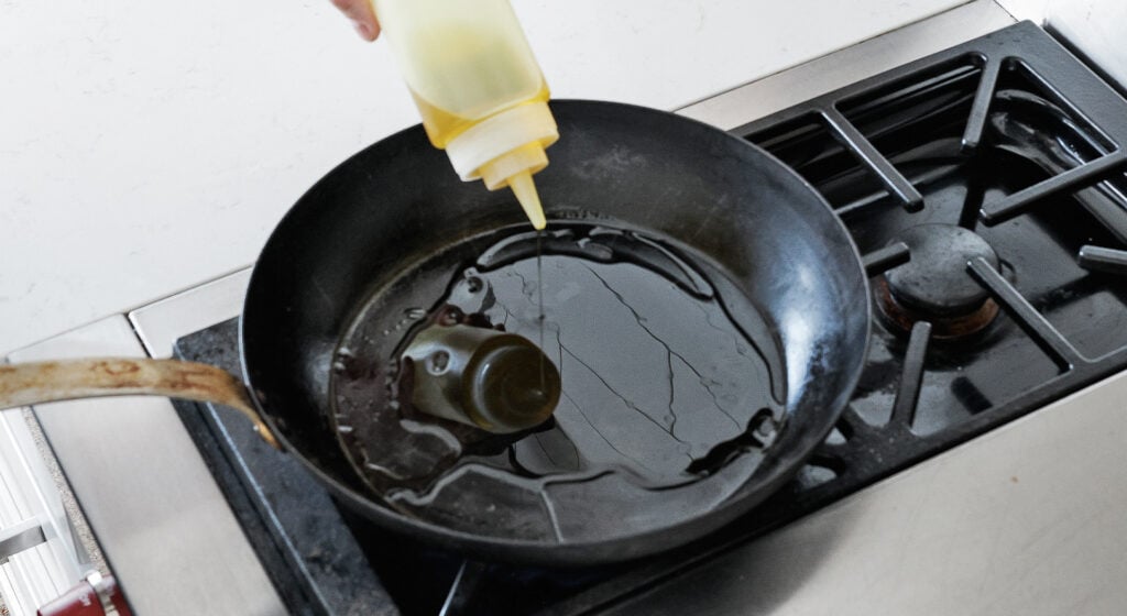 Olive oil heating in a cast iron pan over high heat