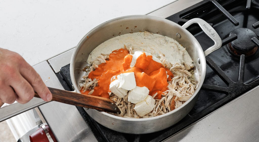 Shredded chicken, cubed cream cheese, buffalo sauce, and ranch melting together in a pan