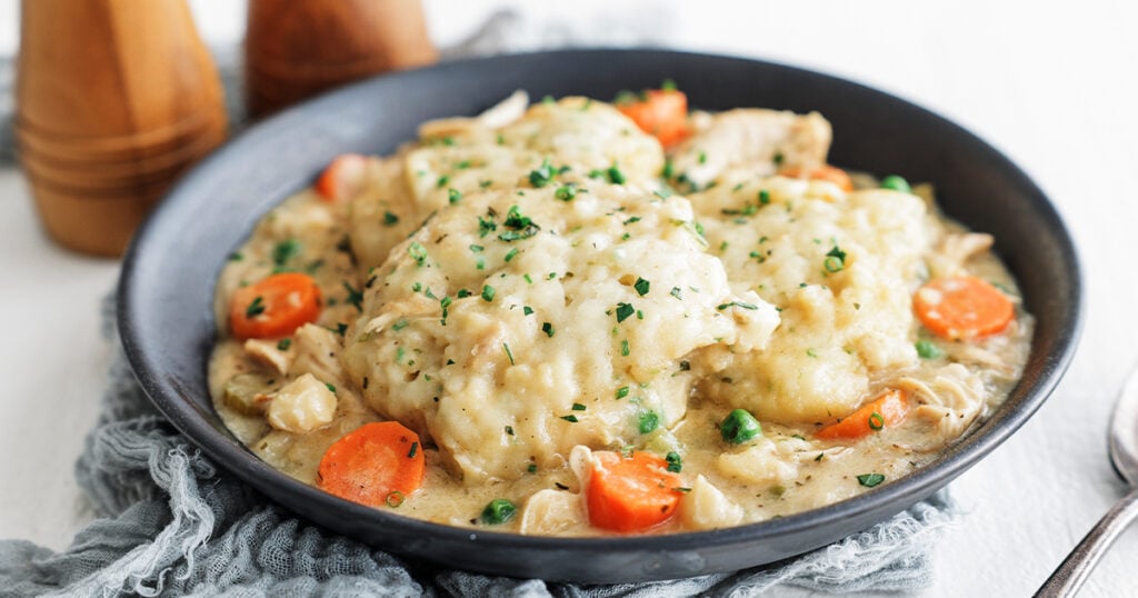 Finished chicken and dumplings garnished with chives, thyme, and parsley