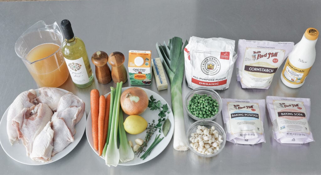 Chicken and dumplings ingredients including bone-in chicken, carrots, celery, leek, flour, buttermilk, and butter