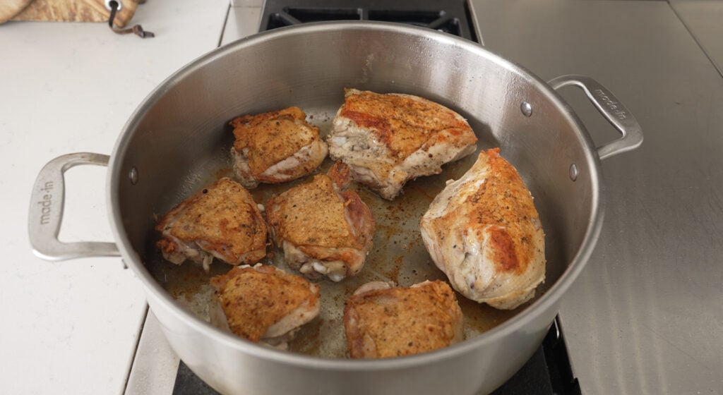 Chicken searing skin side down to a brown crust in a rondeau