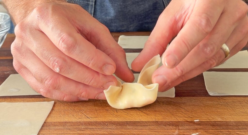 A wonton wrapper folded and pinched closed into the classic four-point crab rangoon shape