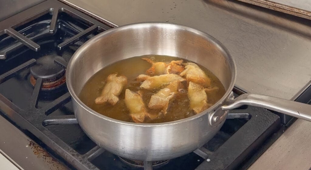 Crab rangoon frying in a saucepan of oil