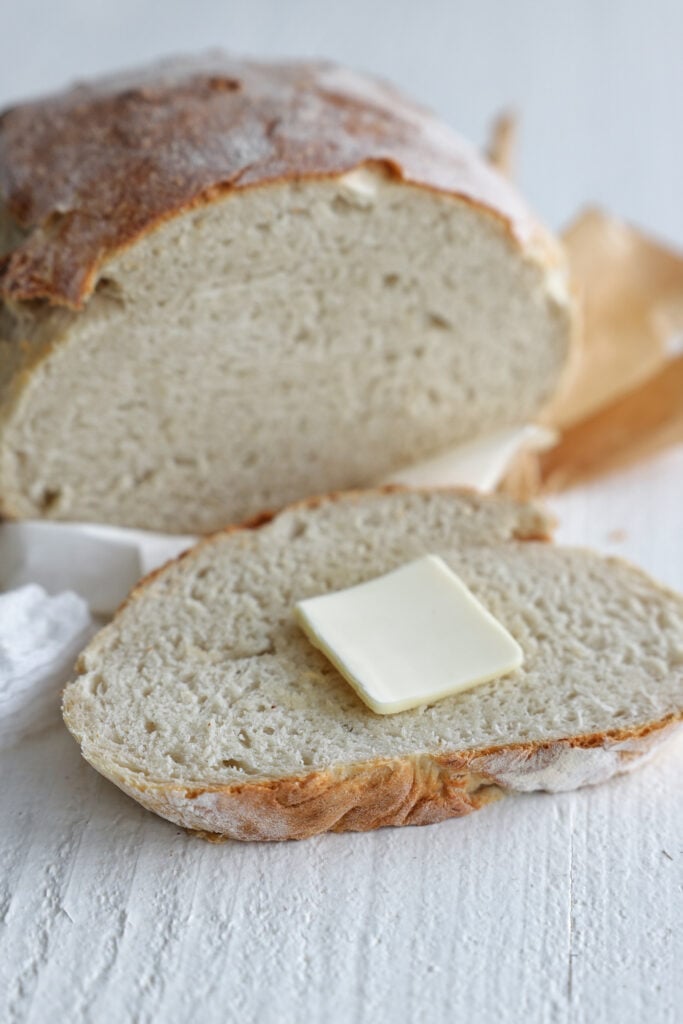 Crusty homemade dutch oven bread sliced open with butter