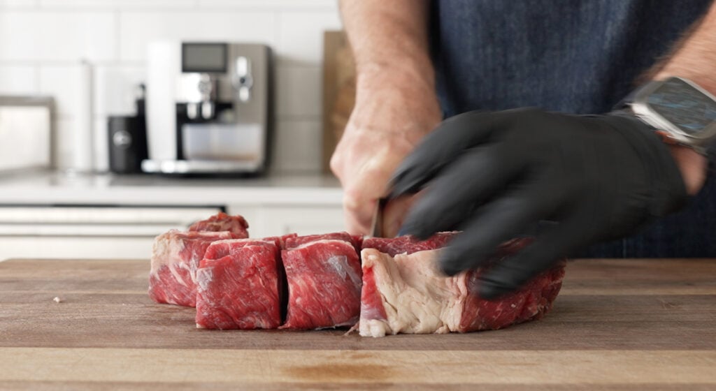 Beef chuck and short ribs cut into 2 inch cubes on a cutting board for peposo