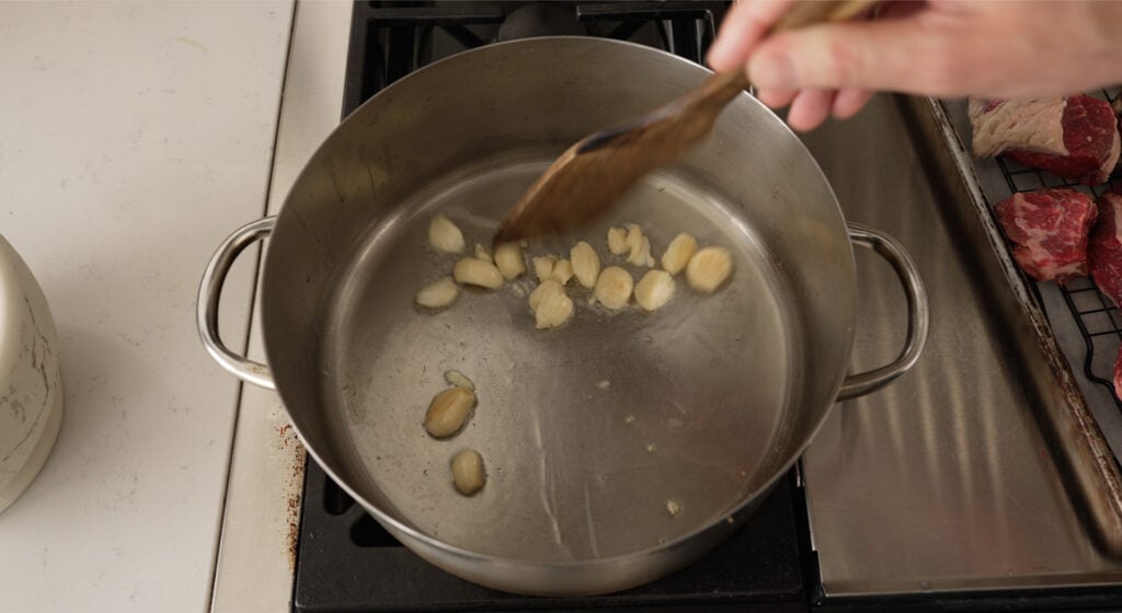 Smashed garlic cloves toasting in beef tallow to make garlic oil