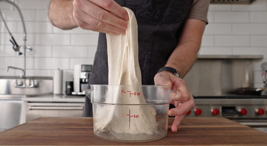 Smooth kneaded pizza dough pulling away from the sides of the mixing bowl