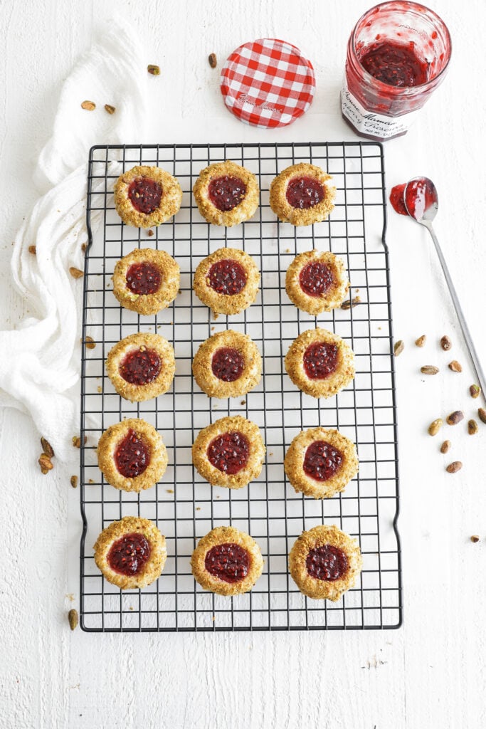baked raspberry thumbprint cookies  on a wire rack
