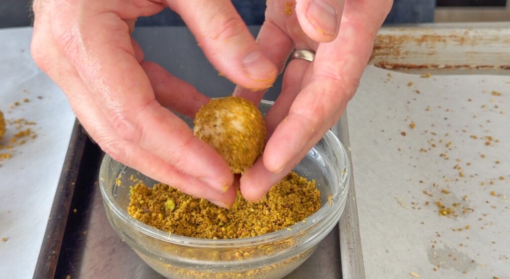 rolling dough balls in finely ground pistachios