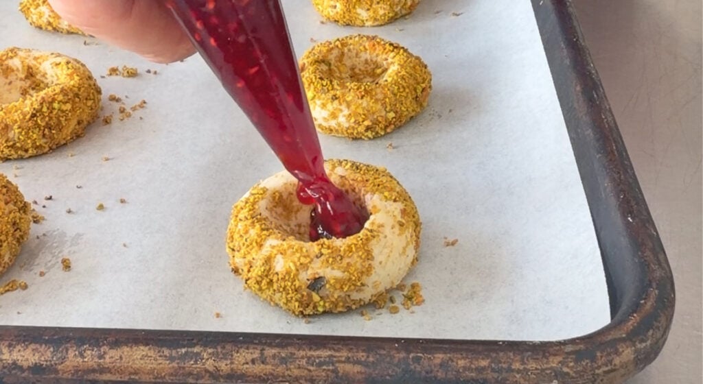 raspberry preserves into the center well of each pistachio-coated cookie