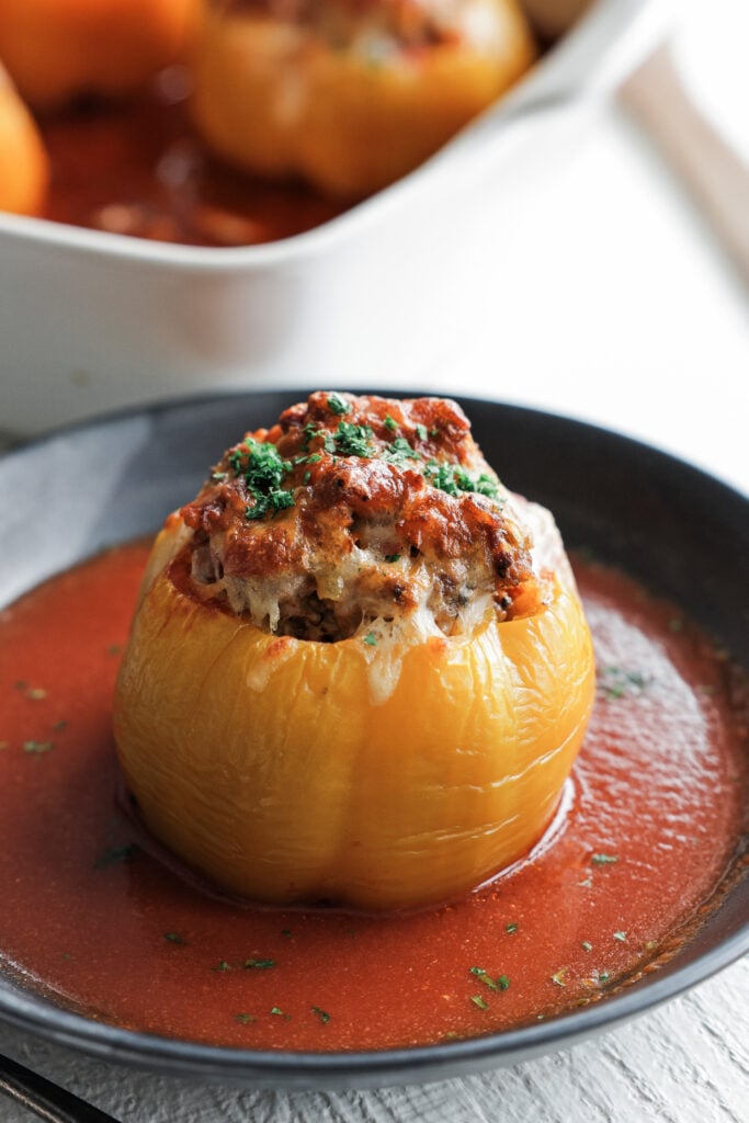a stuffed pepper sliced open on a plate with beefy tomato sauce and parsley