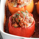 a stuffed pepper sliced open on a plate with beefy tomato sauce and parsley