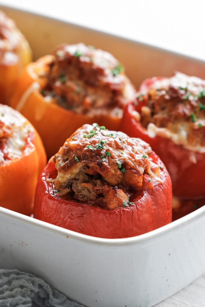 a stuffed pepper sliced open on a plate with beefy tomato sauce and parsley