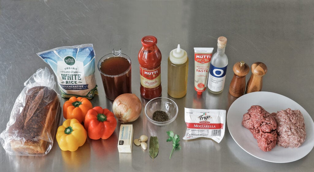 the stuffed peppers ingredients laid out, meats, sweet peppers, rice, bread, and aromatics