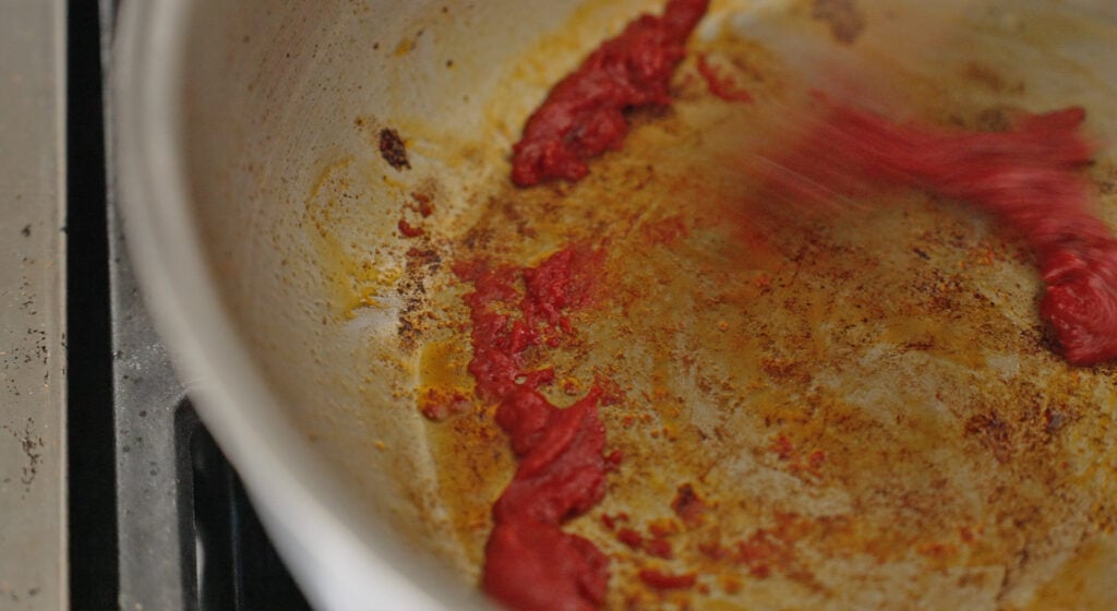tomato paste cooking to a rust color in a saucepan
