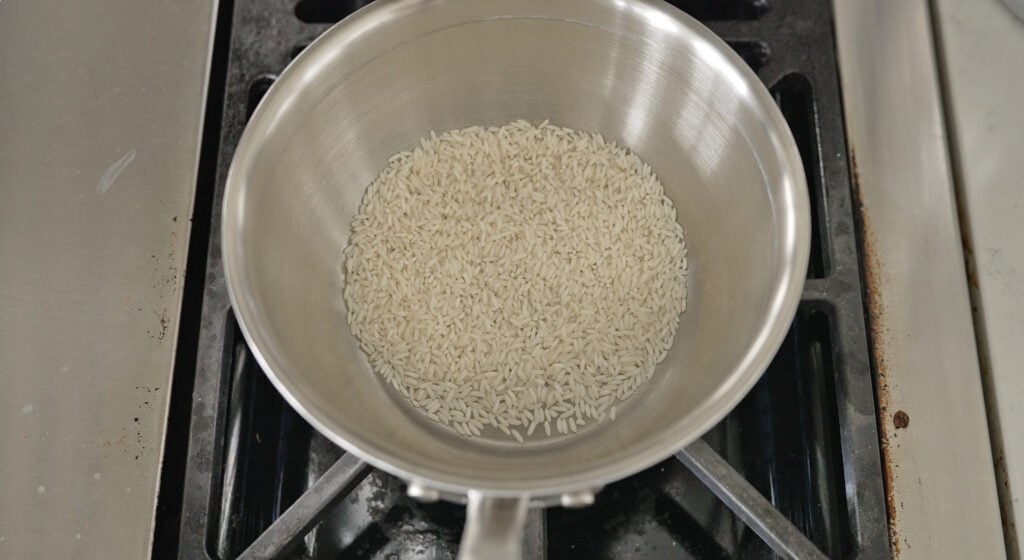 long grain rice toasting to a milky white color in a pot