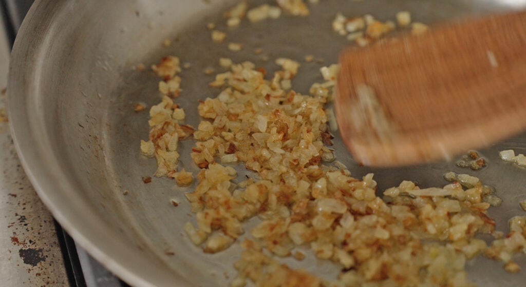 onions and diced peppers browning in a saute pan for the filling