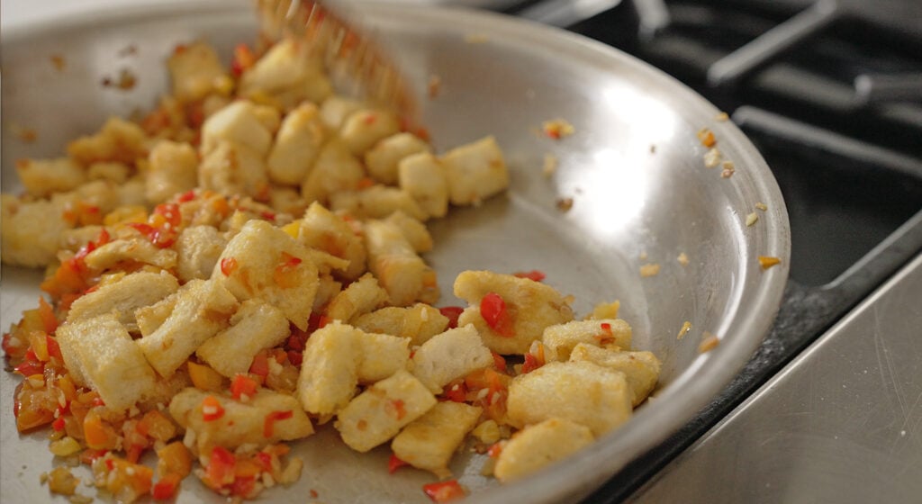 cubed crustless bread soaking into the onion and pepper mixture